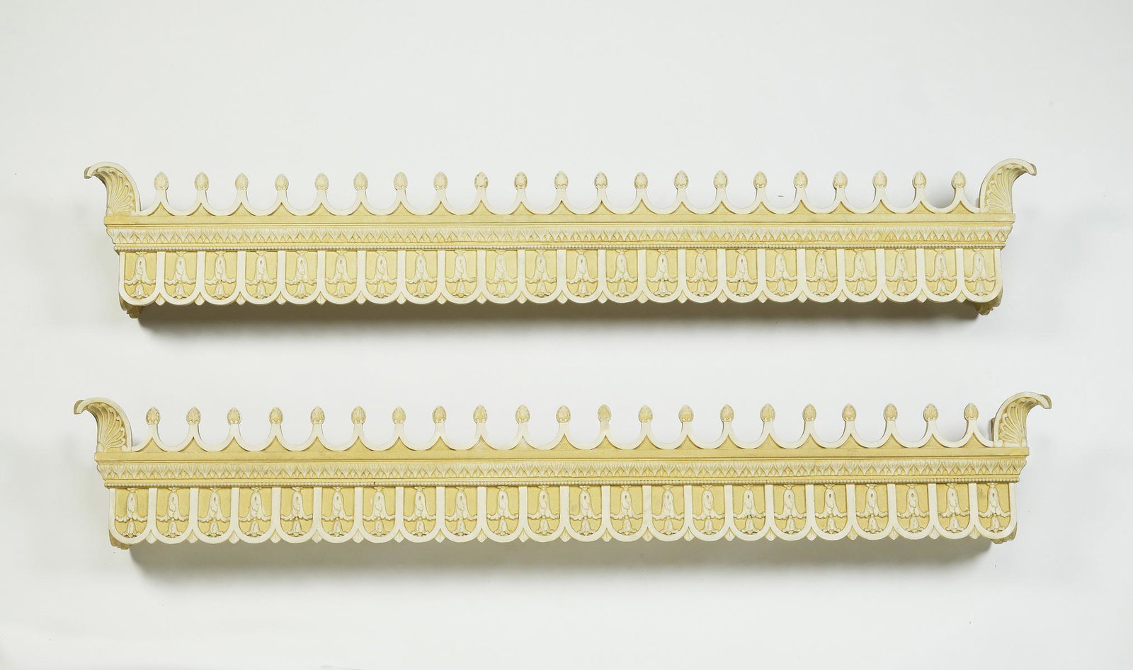 Pair of carved and paint-decorated cornices, 68"l: Pair of carved and paint-decorated cornices, each having a scalloped gallery accented with scallop finials rising above the relief carved apron depicting acanthus leaves, 11"h x 68"l x 8.5"d.