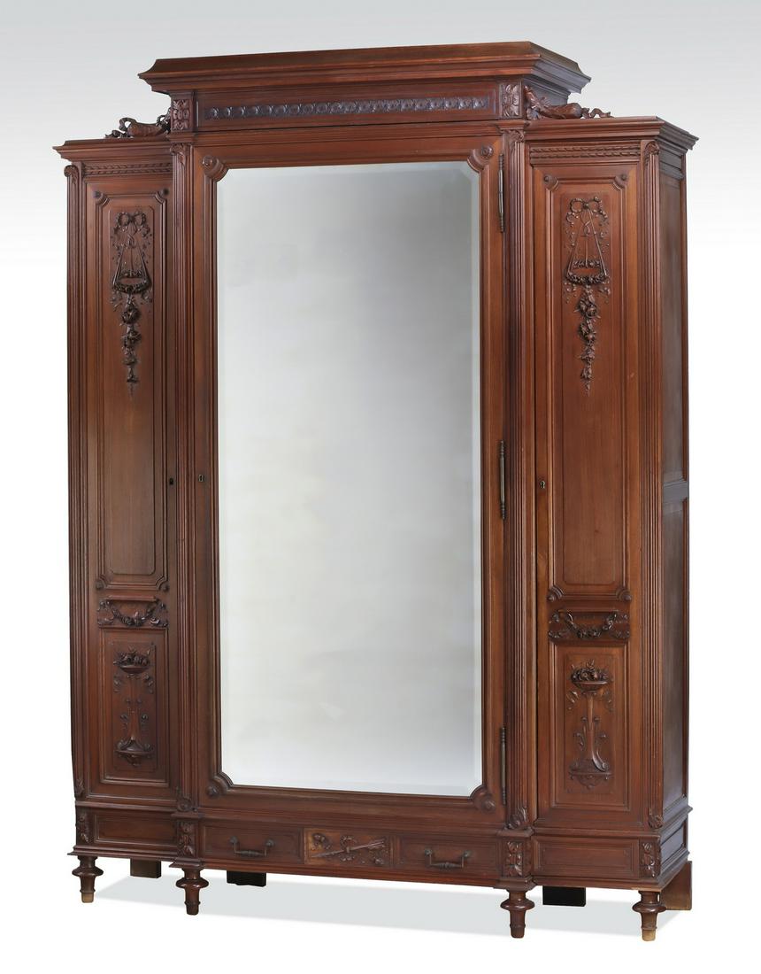 19th c. French walnut armoire with floral carvings: French Renaissance Revival walnut armoire, late 19th century, having a straight cove molded pediment above a frieze of flowers, surmounting a breakfront cabinet centering a door with a double beveled 