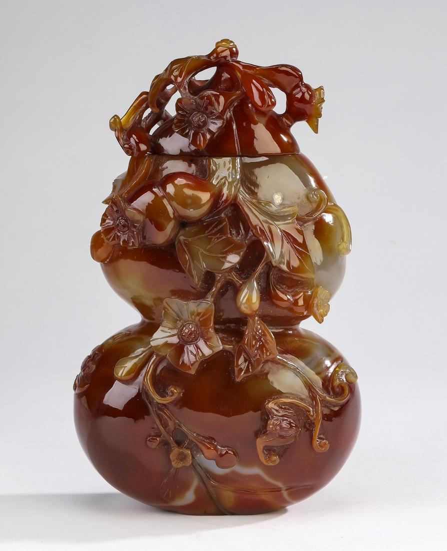 Chinese carnelian double gourd lidded urn, 10"h: Chinese carved carnelian double gourd lidded urn, the lid and body carved with a pierced cage of high relief prunus branches, peaches, and bats, 10"h x 5.75"w x 3"d.