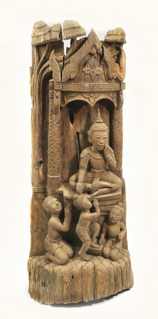Rustic Balinese carving of the Buddha, 43"h: Rustic Balinese carving of the Buddha, carved from a single log, depicting the Buddha seated with louhans at his feet, having a hanging mechanism attached en verso, 43"h x 14"w x 7"d.