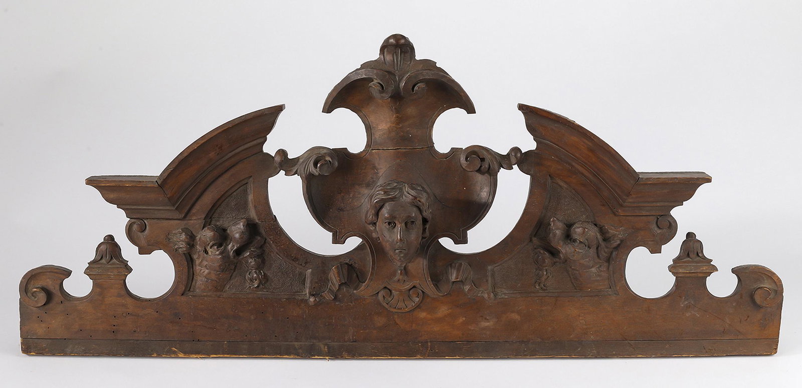 19th c. Continental relief carved walnut pediment: 19th century Continental pierced and relief carved Neoclassical style walnut pediment, having a female mask on an elaborated crest background, flanked by carved ribbons and naturalistic motifs, 13"h x