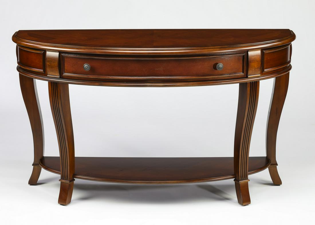 Book matched mahogany console table with shelf. 52"l: Book matched and feather banded mahogany console table in the Regency taste, having a D-shaped top with molded edges over a long frieze drawer, rising on reeded cabriole legs joined by a low shelf ter