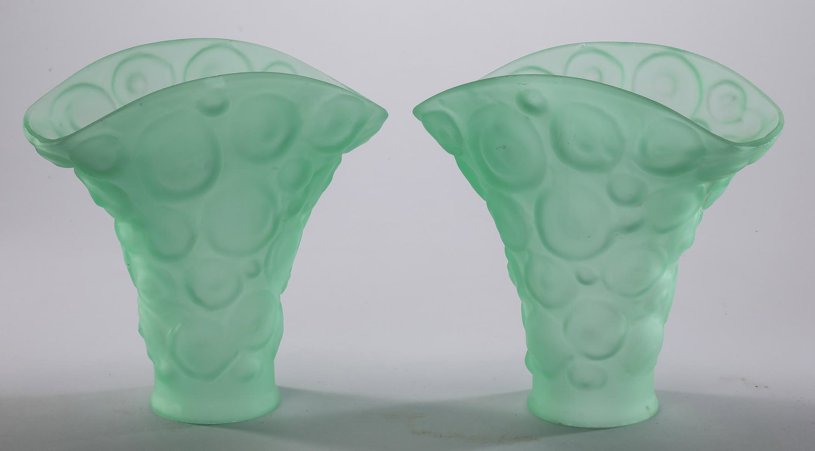 (2) Contemporary seafoam art glass fan shades: Pair of contemporary art glass fan shades, executed in seafoam satin glass with stylized molded coin spot decoration, 8.75"h x 8.5"w x 4.5"d; fitter 3.25"dia.