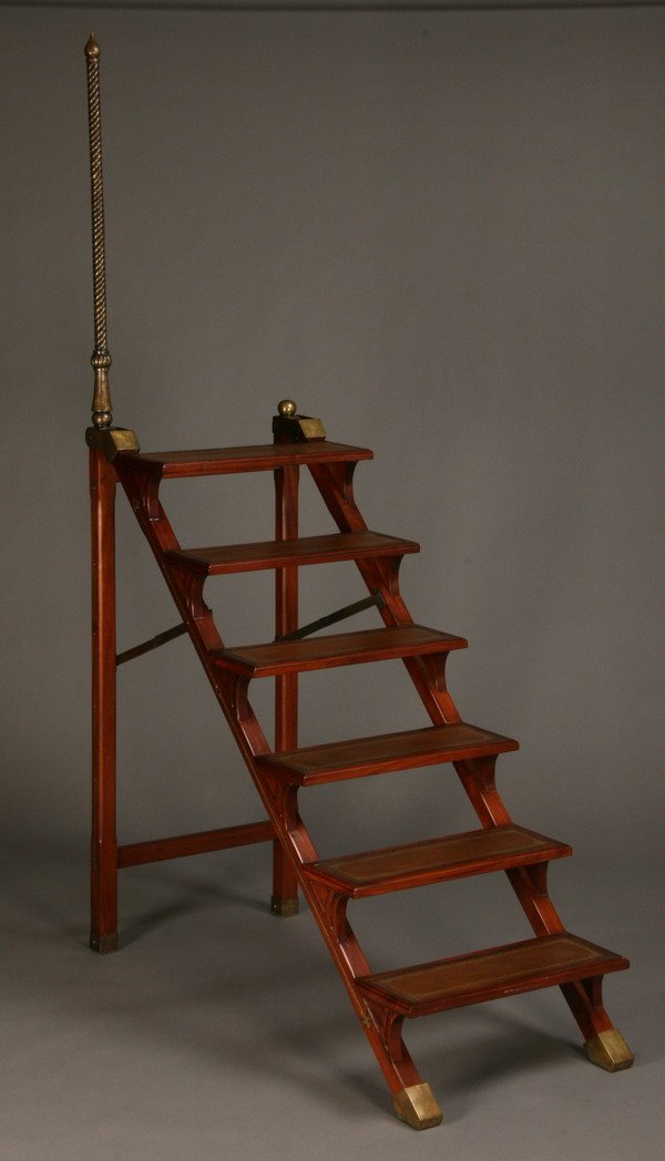 Mahogany library ladder: Mahogany six step library ladder with bronze accents, steps inset with gold tooled leather, and collapsible hinges for compact storage, 50"h x 24"w x 53"l (88"h to top of bronze hand support).