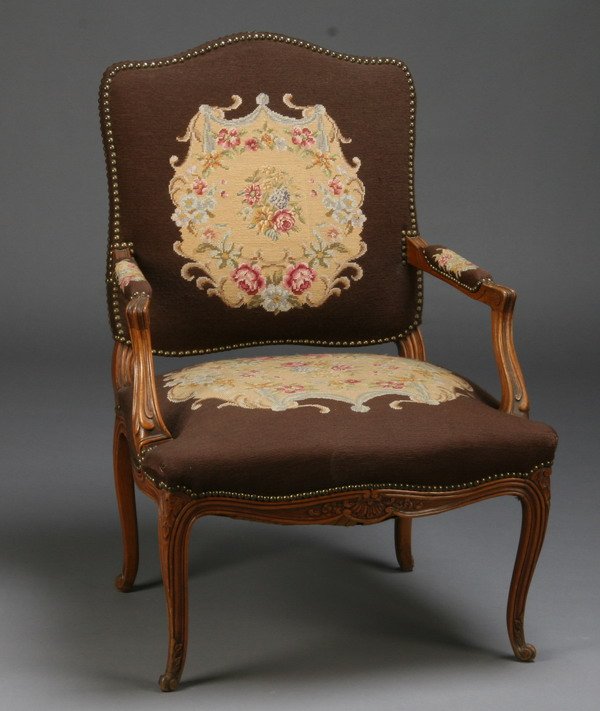 19th c. French needlepoint arm chair: Late 19th century French Provincial arm chair with chocolate brown needlpoint upholstery accented with petit point floral designs, 38"h x 26"w.