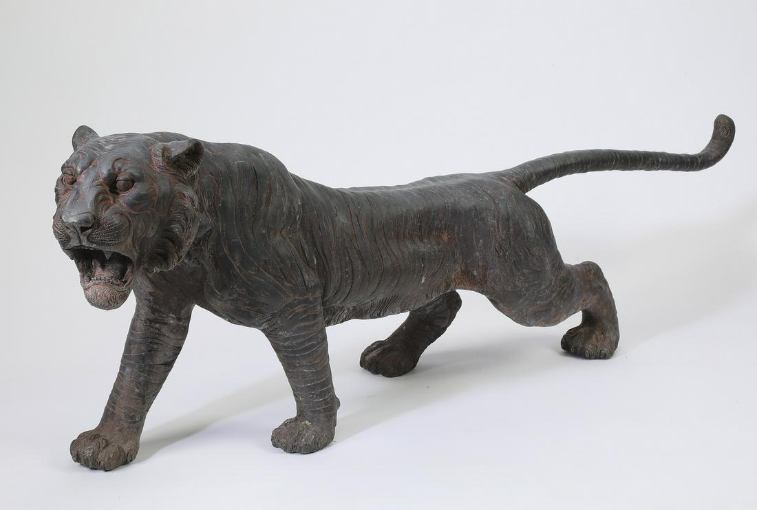 Patinated bronze sculpture of a tiger: Patinated bronze sculpture of a tiger, depicting the prowling predator cat with its mouth open in a roar, 18"h x 48"l x 8"w.