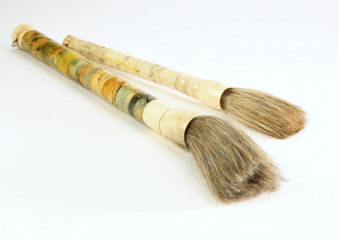 (2) Chinese calligraphy brushes: Group of (2) Chinese calligraphy brushes, early to mid 20th century, including (1) executed in bone engraved with scenes and text, 15.5"l x 2"dia, and (1) executed in hardstone in green with russet in