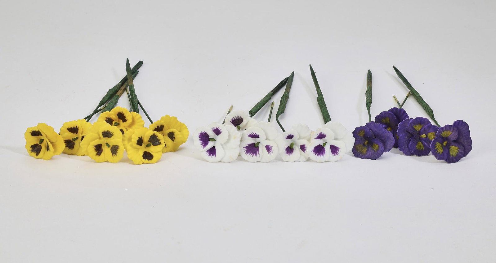 Group of (15) porcelain pansies: Group of (15) porcelain pansies, late 20th century, in hues of yellow, purple and white, 4"l x 1.5"dia.