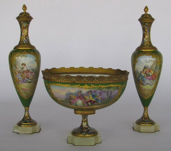 3-piece Sevres garniture set, artist signed: 3-piece Sevres garniture set of bronze mounted porcelain with champleve' enamel, artist signed "M. Gilloue...", each on an onyx base. Oval bowl: 9"h x 10"l; covered urns: 17"h x 7"w.