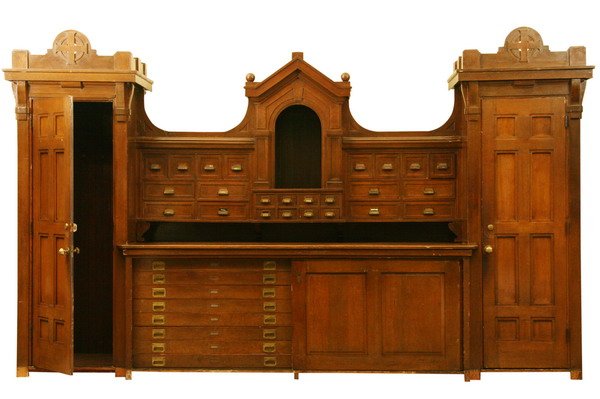 19th century American carved oak wall unit, 15' l: Late 19th century American carved oak wall unit, the center section with 16 drawers behind sliding doors, each drawer 51"l x 32"d, flanked by two storage closets 91"h x 32"w x 31"d. Overall size 9 ft 