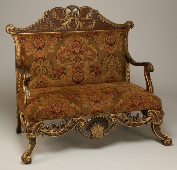 Parcel gilt carved mahogany settee: Carved and parcel gilt mahogany settee with arched crest and oversized shell carvings at the apron, upholstered in tapestry-style chenille, 50'h x 50"l.