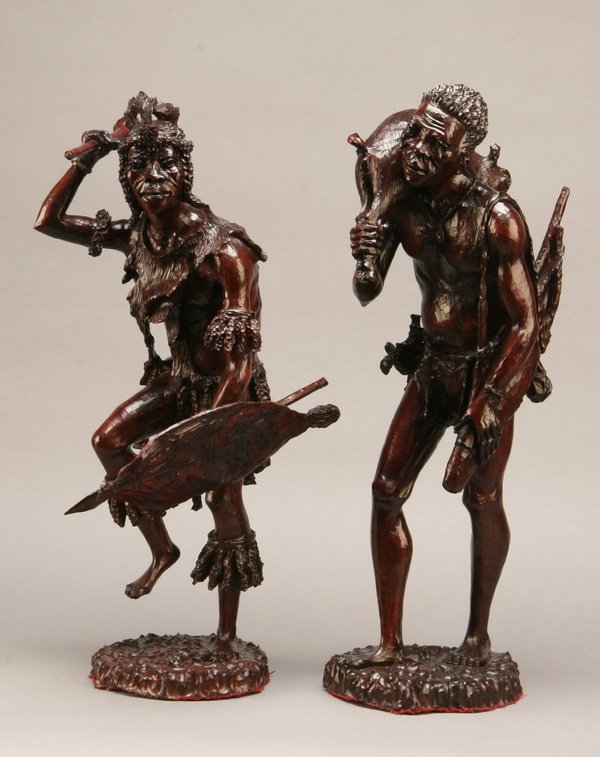 Pair of carved African figures, artist signed: Pair of finely carved African figures depicting a hunter carrying a boar and a warrior in war dance regalia with shield, spear and club, artist signed Takawana, each 22" tall.