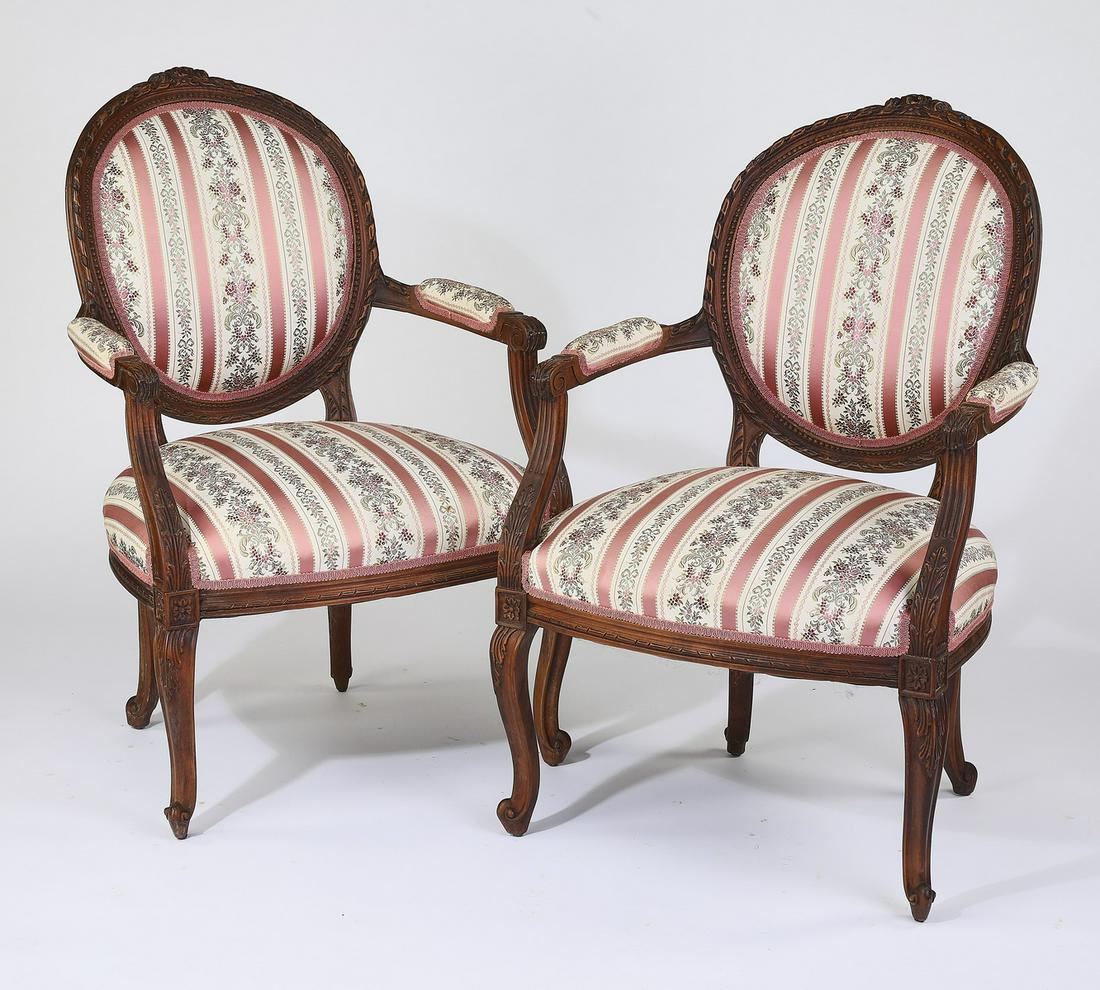 (2) Early 20th c. Louis XV style fauteuils: Pair of Louis XV style fauteuils, early to mid 20th century, executed in walnut, each having a foliate cartouche surmounting the ribbon carved frame centering the cabachon back upholstered in an alter