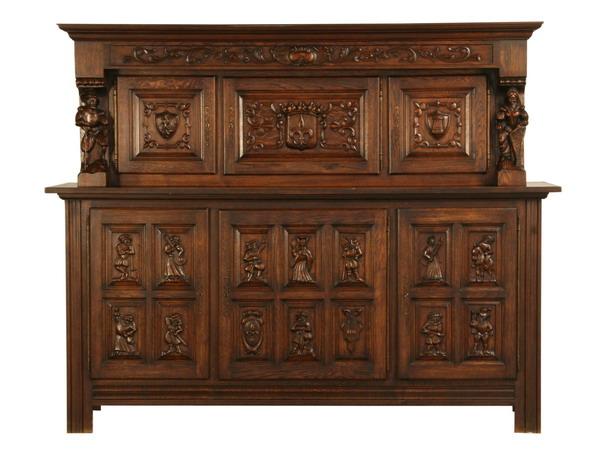 Early 20th c. oak Jacobean-style buffet: Early 20th century carved oak Jacobean-style Spanish buffet with relief carved upper door panels depicting coats of arms flanked by fully formed male and female court figures, over a three door base c