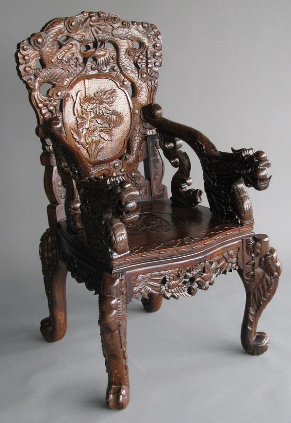 Carved Chinese rosewood arm chair: Carved rosewood Chinese export arm chair, relief carved throughout with dragon motif, the arm rests in the form of dragon scales terminating in carved dragon heads, each chair leg in the form of a car