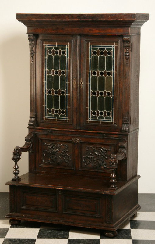 19th c. English hall bench bookcase: Unique 19th century 2-part English Jacobean-style hall bench bookcase with leaded glass doors, lift top seat, and hidden storage compartment behind a drop front carved panel, 84"h x 45"w x 33"d.