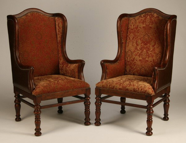 Pair of wingback chairs with leather backs: Pair of Jacobean-style wingback chairs with exposed mahogany frame upholstered in tapestry style chenille with nailhead trim, the back and sides upholstered in leather, 50"h x 26"w x 20"d.