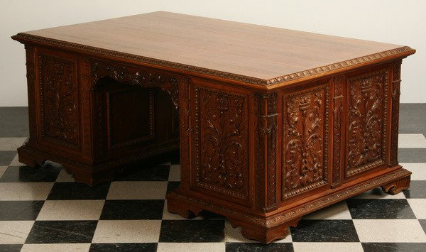 19th c. carved walnut partners' desk: Late 19th century carved Italian walnut partners' desk with central frieze drawer flanked by concealed storage with foliate relief carved door panels, the sides with similar carved panels, 30"h x 74"l