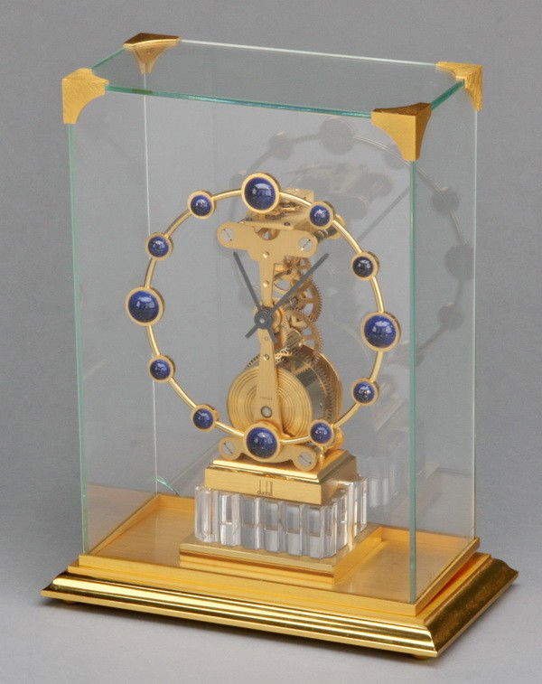 20th c. Dunhill skeleton clock: 20th century Dunhill skeleton clock under gilt bronze trimmed glass case, 9"h x 7"w x 4"d.