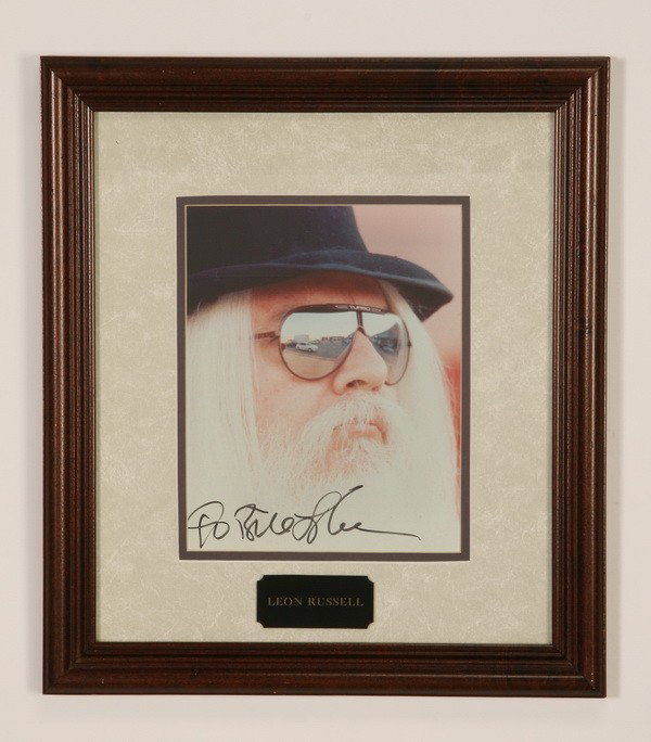 Leon Russell autographed photo: Framed autographed photo of well-known versatile songwriter and musician Leon Russell, overall size including frame 17.5"h x 15.5"w.