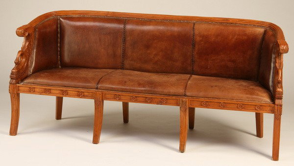 Carved teakwood settee in leather: Carved teakwood settee with swan form arms, upholstered in leather with nailhead trim, 32.5"h x 70"l x 22"d.