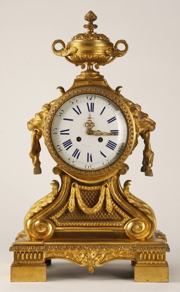 19th c. French dore' bronze clock: Late 19th century Neoclassical style dore' bronze clock with superbly chased case, the clock face surmounted by a lidded urn, the sides with lion masks holding rings, originally retailed by noted Pari
