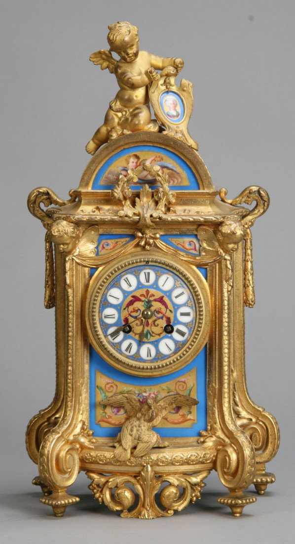 19th c. bronze and porcelain clock: Early 19th century dore' bronze and porcelain clock, with fully formed cherub at the pediment holding a handpainted portrait, the sides with handpainted floral filled urns, the clock face with handpai