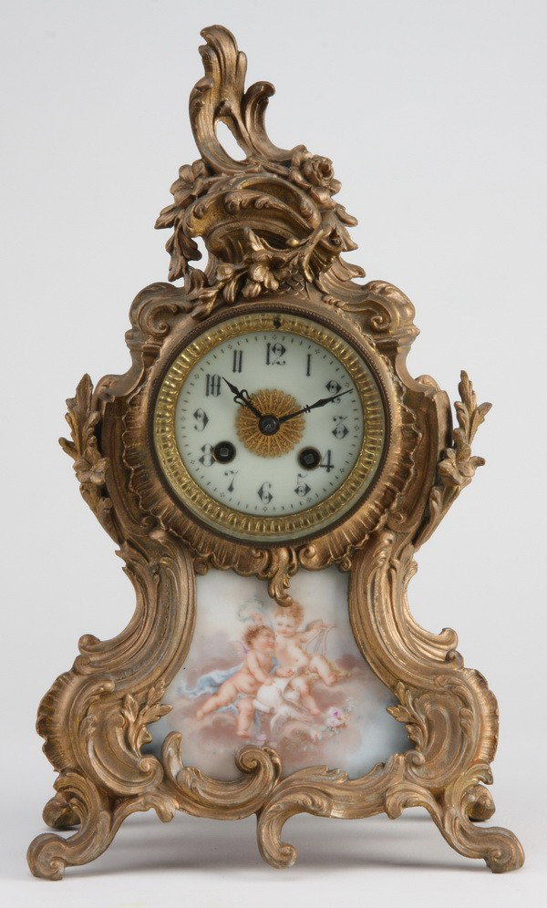 19th c. French bronze and porcelain clock: Late 19th century French Louis XV style dore' bronze clock with a central Sevres-style hand painted porcelain plaque depicting winged putti, 15"h x 9"w x 6"d.