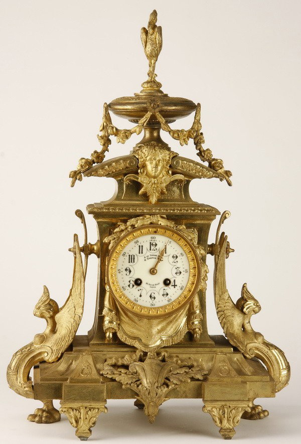 19th c. French dore' bronze clock: 19th century French Renaissance Revival dore' bronze clock, the clock face surmounted by a maiden's mask and lidded urn, flanked by stylized winged birds, the porcelain clock face encircled with finel
