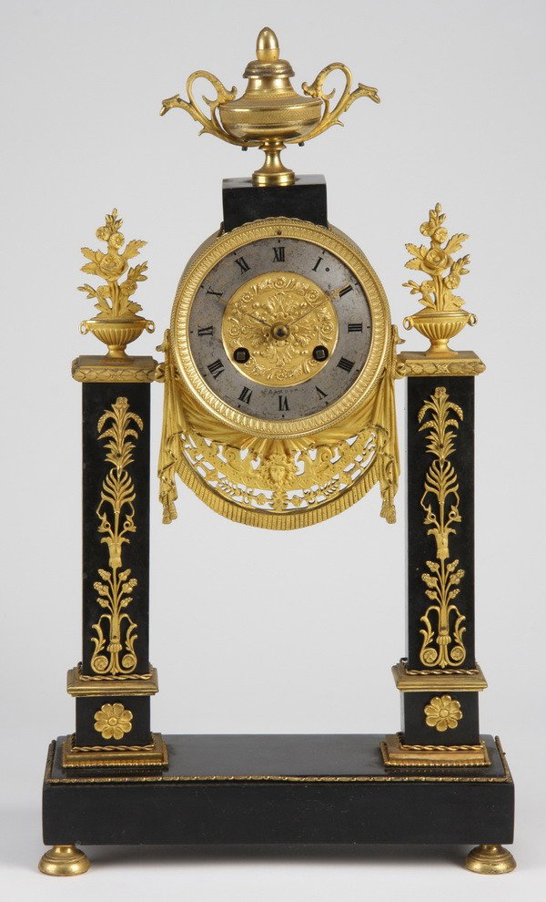 19th c. patinated and dore' gilt bronze clock: 19th century Napoleon III Empire patinated and dore' gilt bronze clock, the clock face surmounted by a lidded urn, with a finely chased drapery swag beneath, all flanked by patinated columns surmounte