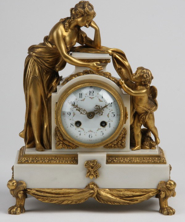 19th c. French dore' bronze and marble clock: Late 19th century Louis XV style dore' bronze figural clock with standing maiden and winged cherub flanking the clock face, resting on a white marble base with gilt bronze surmounts, 12.5"h x 10"w x 5