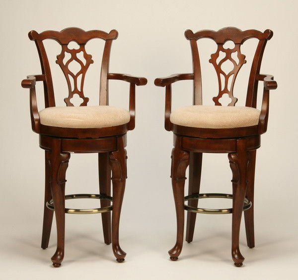 (2) Mahogany swivel bar stools: Pair of mahogany Chippendale-style swivel bar stools with brass footrest, 46"h x 24"w x 19"d.