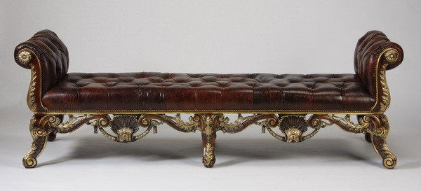 Oversized carved bench in tufted leather: Oversized carved and parcel gilt mahogany bench, the apron with pierce carved shell and scrolling acanthus leaf accents, upholstered in brown tufted leather with nailhead trim, 31"h x 93"l x 30.5"d.