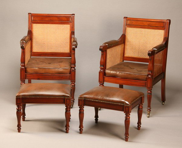 Pair of carved mahogany arm chairs w/ stools: Pair of carved mahogany British Colonial style arm chairs with woven cane backs, seats and sides, and removable cushions of tufted leather with matching foot stools, chair 41"h x 25"w x 19"d, foot sto