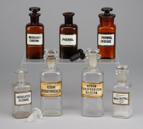 (7) Original apothecary glass bottles: Group of 7 apothecary glass bottles with stoppers, from the original Pollock Bailey Pharmacy in New York City, ranging in size from 5"h to 7"h.