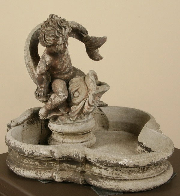 Cast stone fountain with cherub and dolphin: Cast stone fountain of a cherub holding a dolphin, 27"h x 30"w x 27"d.