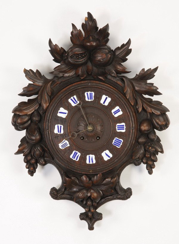 19th c. carved Black Forest wall clock: Late 19th century German carved oak Black Forest wall clock, the clock face with enameled Roman numerals encircled by carved clusters of pomegranates and grapes, 27"h x 18"w.