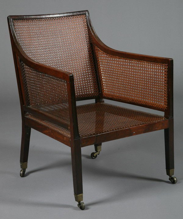 19th c. English mahogany chair: Late 19th century mahogany bergere with caned sides, seat and back, on bronze casters, 35"h x 25"w x 24"d.