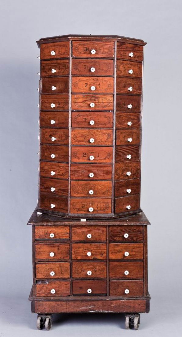 19th c. country store cabinet on wheels: Late 19th c. octagonal shaped country store pine cabinet, the top section with 80 triangular drawers, the base with 24 standard drawers, all with original porcelain pulls, resting on four original iro