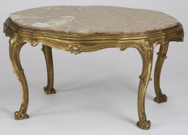 20th c. Italian marble top coffee table: 20th century Italian oval gilt wood coffee table with inset pink and tan marble top, carved apron, and cabriole legs terminating in scroll feet, 19.5"h x 37"w x 26"d.