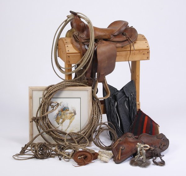 Grouping of western, cowboy accoutrements: 20th century grouping of western paraphernalia and cowboy accoutrements, includes (1) tooled leather saddle, (1) blanket, (1) pair of tooled leather stirrups, (2) sets of spurs, (1) pair of black leat
