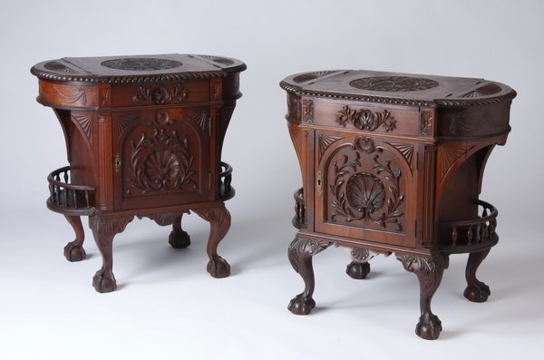(2) Carved mahogany side tables: Pair of carved mahogany side tables with overall shell and foliate designs, the oval top with a central foliate medallion flanked by demilunes with fan motifs opening to storage space, the body with a
