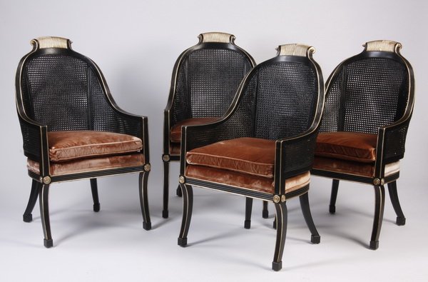 (4) Ebonized wood and cane chairs: Set of four mid to late 20th century ebonized and parcel gilt carved wood chairs, the rounded cane back and arms surmounted by a scrolling fluted crest, with a dusty rose colored velvet seat, on splay
