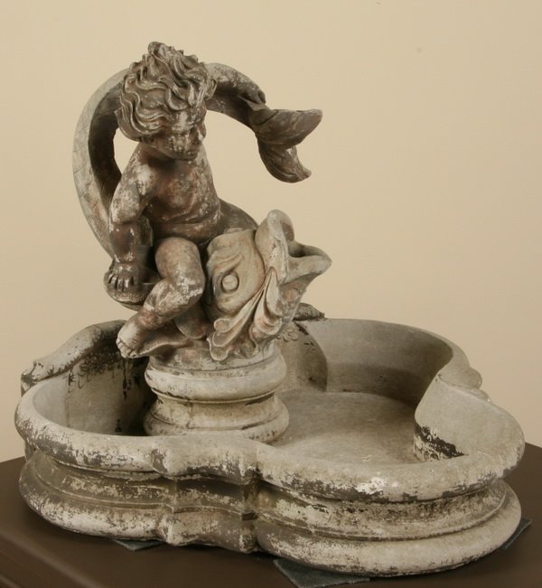 Cast stone fountain with cherub and dolphin: Cast stone fountain of a cherub holding a dolphin, 27"h x 30"w x 27"d.