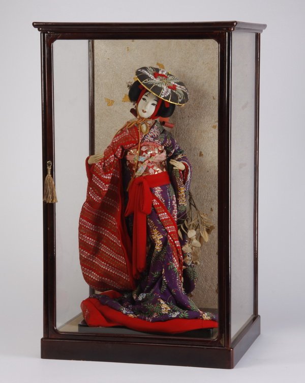 Mid 20th c. geisha doll with glass case: Mid 20th century Japanese geisha doll, handcrafted of fabric and silk and dressed in a kimono costume, size with stand 23.5"h x 12"w x 9.5"d; displayed within a glass and lacquered wood case, overall