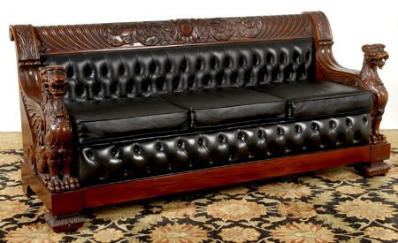 Carved mahogany sofa, after R.J. Horner: Magnificently carved mahogany three cushion sofa, after the original by R.J. Horner, upholstered in black tufted leather with a scroll back crestrail carved with a central cabochon flanked by scrollin