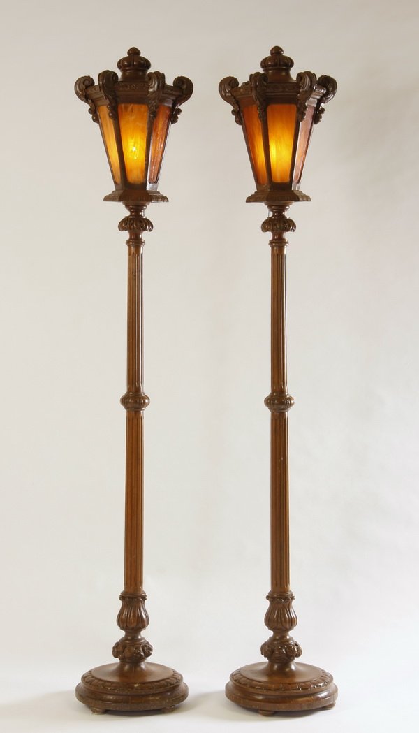 (2) Mid 20th c. floor lamps: Pair of mid 20th century carved and stained maple floor lamps, formed as street lights with foliate details, the hexagonal lanterns with orange slag glass panels, each 80"h x 14.5"w.