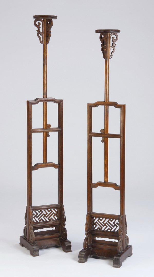 (2) Early 20th c. Chinese candle stands: Pair of early 20th century Chinese huanghuali wood candle stands, the inverted U-shaped frame joined by two humpback stretchers, surrounding an adjustable pole with a locking mechanism supporting the 