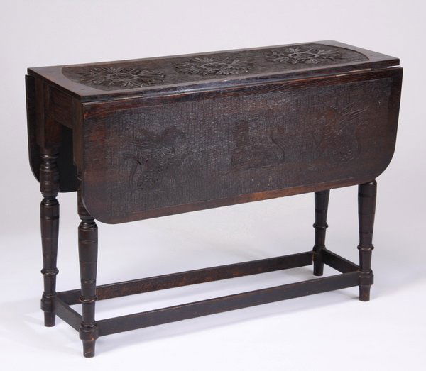 19th c. English carved oak drop leaf table: 19th century English oak drop leaf table with incised and chip carved designs, the top with a repeating floral motif, each drop leaf with a central sphinx flanked by chimera, all raised on tapering tu