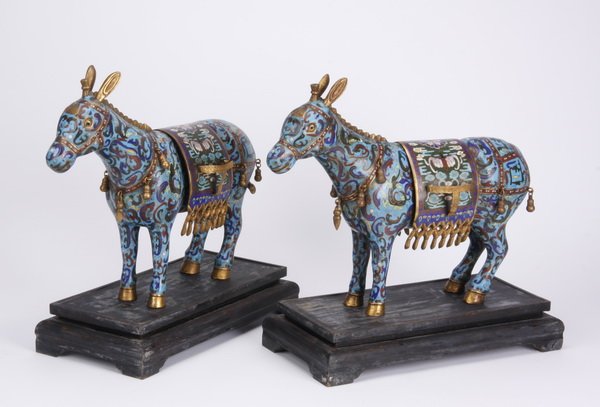 (2) Mid 20th c. Chinese cloisonne' donkeys: Pair of mid 20th century Chinese cloisonné and brass inlaid donkeys, each with a removable saddle blanket, resting on an ebonized carved wood base, 16.5"h x 15.5"w x 7.5"d.